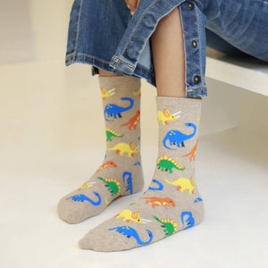 Gray socks with colorful dinosaur pattern worn by a child in denim jeans.