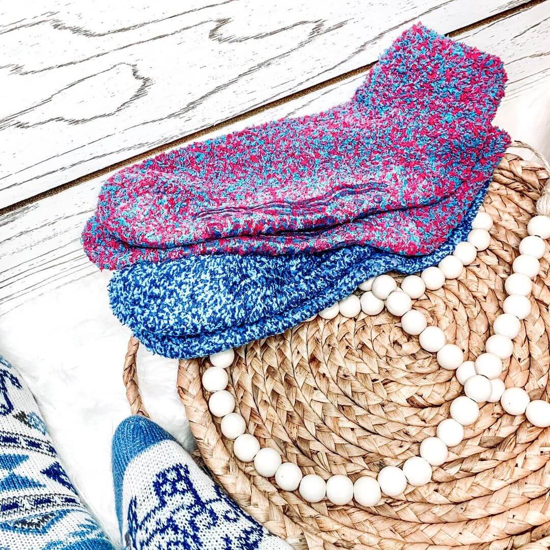 Stack of colorful knitted socks on a woven mat with beads