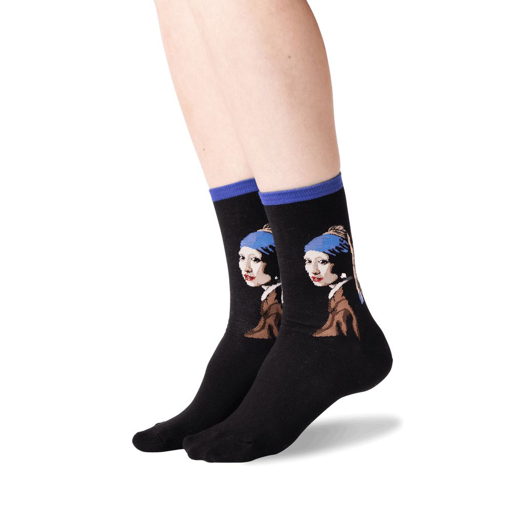 A pair of black crew socks worn on a person's feet, featuring a graphic print of Vermeer's Girl with a Pearl Necklace in blue, brown, white, and red tones, with solid blue ribbed cuffs.