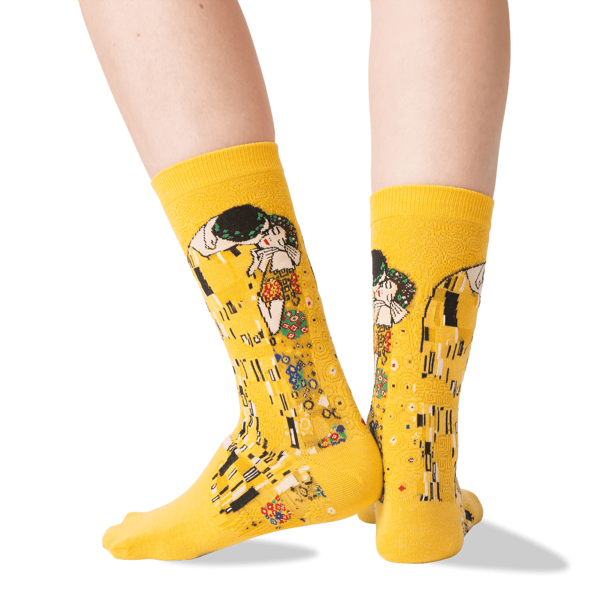 A pair of bright yellow crew socks with a Gustav Klimt 'The Kiss' graphic print, shown on a model's feet against a clean white background.