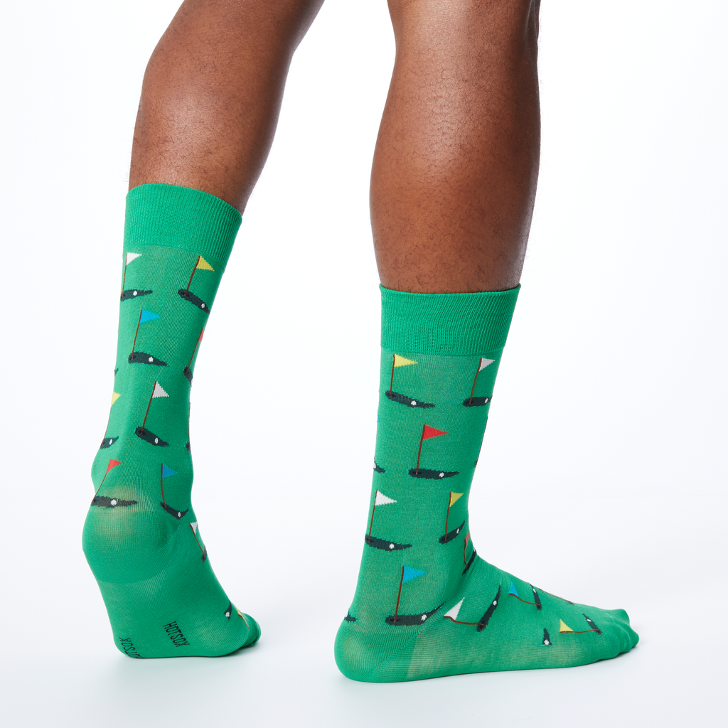 A pair of green crew socks with a pattern of golf flags.