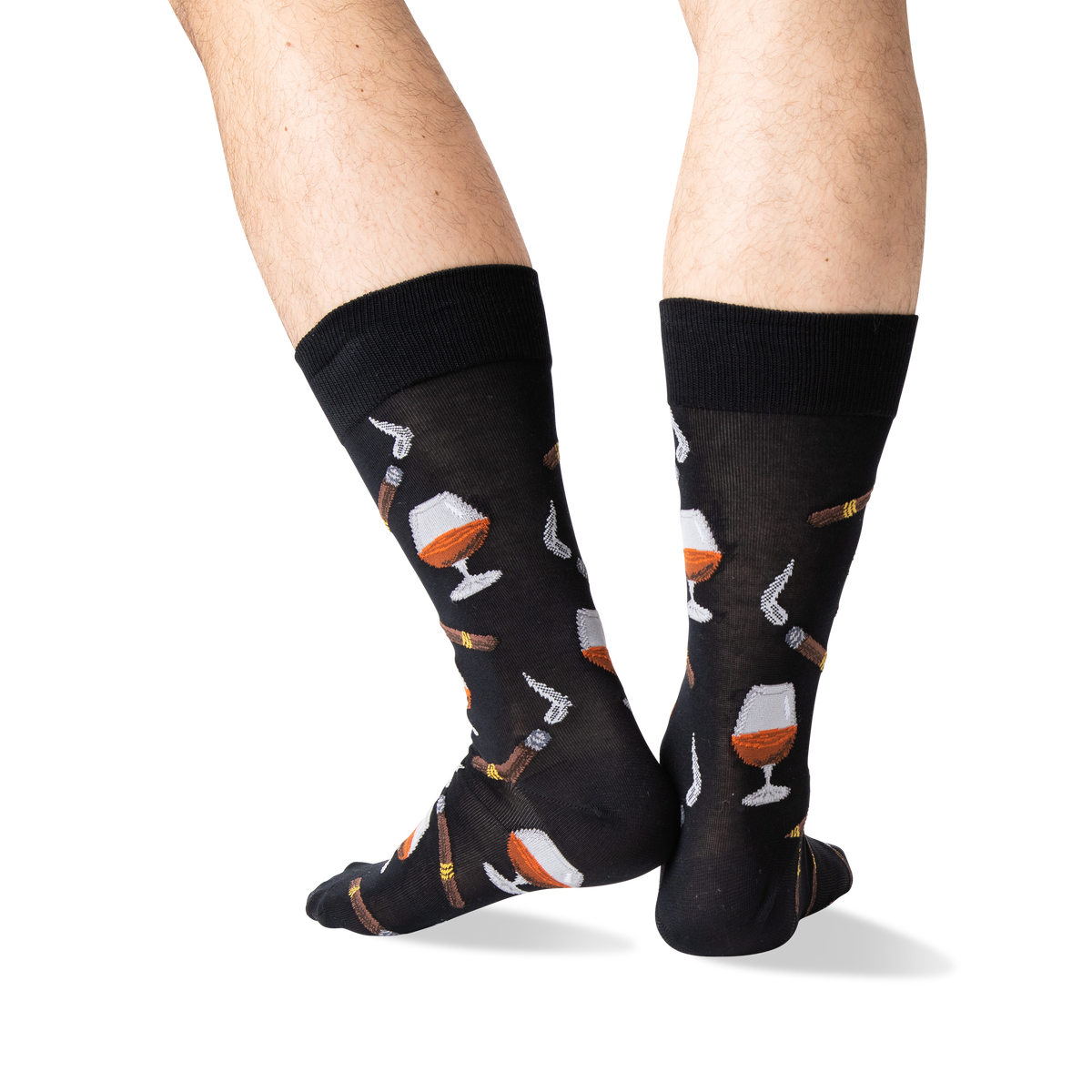 A pair of black crew socks with a pattern of whiskey glasses, cigars, and cigars being lit, shown on a person's legs against a white background.