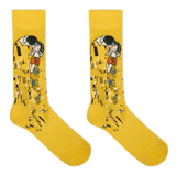 A pair of yellow crew socks featuring a stylized print of Gustav Klimt's 'The Kiss' on the upper leg, displayed against a solid white background.
