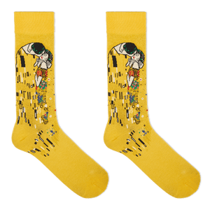 A pair of yellow crew socks featuring a stylized print of Gustav Klimt's 'The Kiss' on the upper leg, displayed against a solid white background.