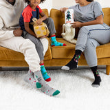 Two adults and a child sitting on a couch wearing colorful socks with various patterns.