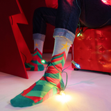 Person wearing festive socks with string lights in a red room.