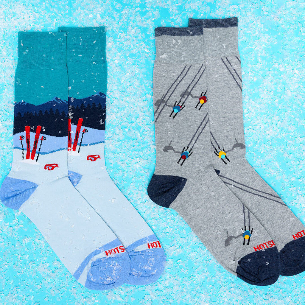 Two pairs of socks with skiing designs on a blue snowy background