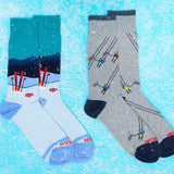 Two pairs of socks with skiing designs on a blue snowy background thumbnail