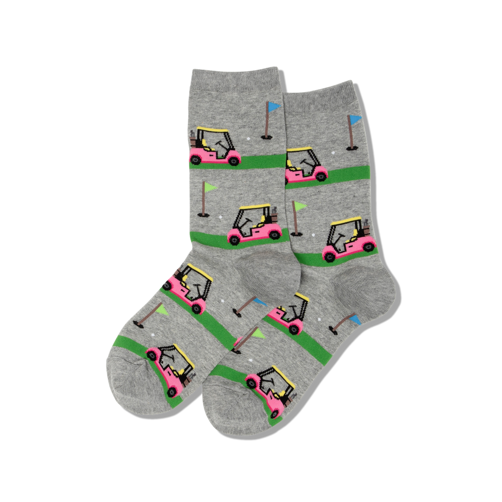 A pair of heather gray crew socks featuring a repeating pattern of pink golf carts on green putting greens with small golf balls and flags.