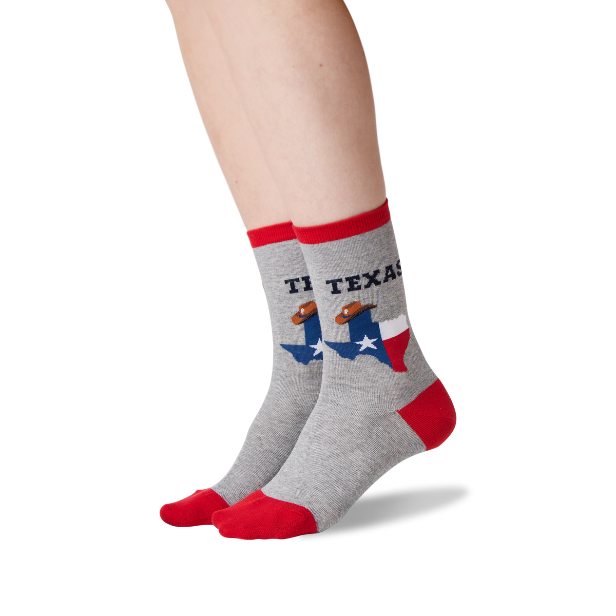 A pair of crew socks worn on a person's feet, shown against a plain white background. The socks are heather gray with red toes, heels, and cuffs, featuring a graphic of the state of Texas with a football player and the text 'TEXAS'.