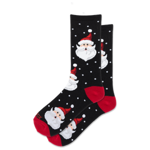 A pair of black crew socks with a festive Christmas pattern featuring Santa Claus faces, red heels and toes, and white polka dots, displayed on a clean white background.