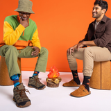 Two men sitting on stools against an orange background
