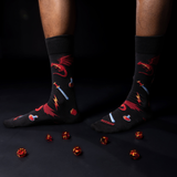 Person wearing black socks with red designs on a dark floor.
