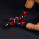 Person wearing black socks with red dragons on a dark surface