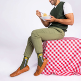 Man sitting on a red and white checkered tablecloth holding a bowl of spaghetti against a white background
