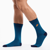 A pair of crew socks with horizontal blue and black stripes, worn on a model's legs against a clean white background. A small orange and yellow logo is visible on the side of the right sock. thumbnail