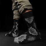 Black socks with white pattern worn by a person on a black background thumbnail