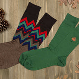 Two pairs of socks with different fall designs on a wooden surface.