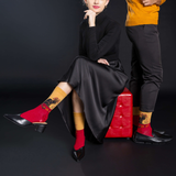 Man and woman posing together against a black background