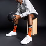 Person sitting on a wooden block holding a basketball against a dark background thumbnail