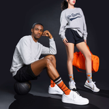 Person sitting on a  basketball, wearing orange and gray basketnall socks.