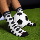 Person wearing black and white soccer patterned socks with a soccer ball on grass