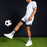 Man kicking a soccer ball on a black background