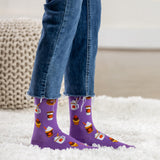 Purple socks with coffee-themed design worn with blue jeans on a white carpet. thumbnail