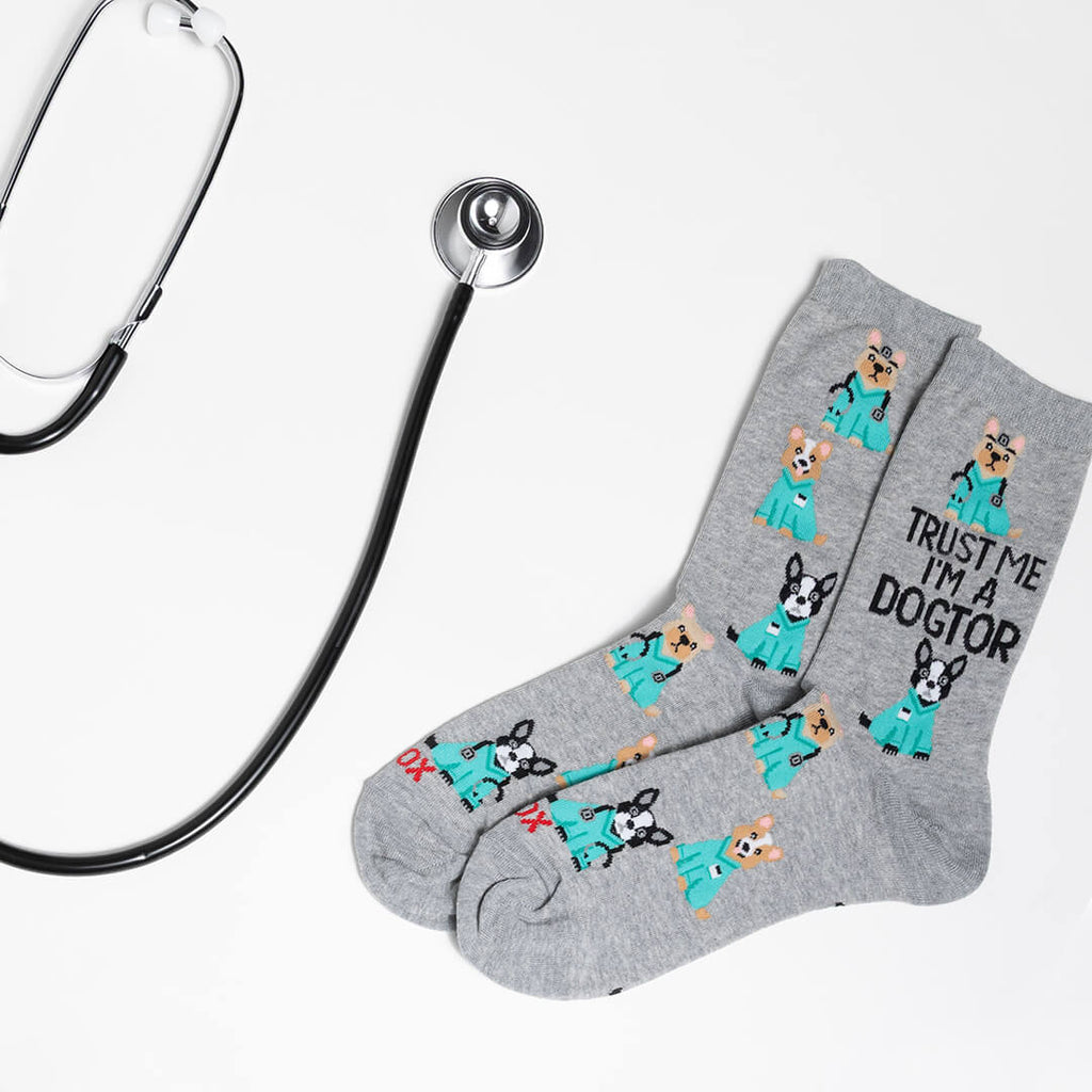 Gray socks with dog illustrations and text, paired with a stethoscope on a light gray background
