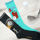 Golf-themed socks with humorous design on a wooden surface with golf club and ball.