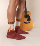 Person wearing patterned socks with a guitar on a neutral background thumbnail