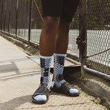 Person wearing black and white striped socks with sandals on a sidewalk. thumbnail
