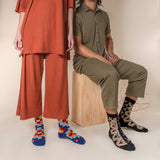 Two people wearing colorful socks with a neutral background