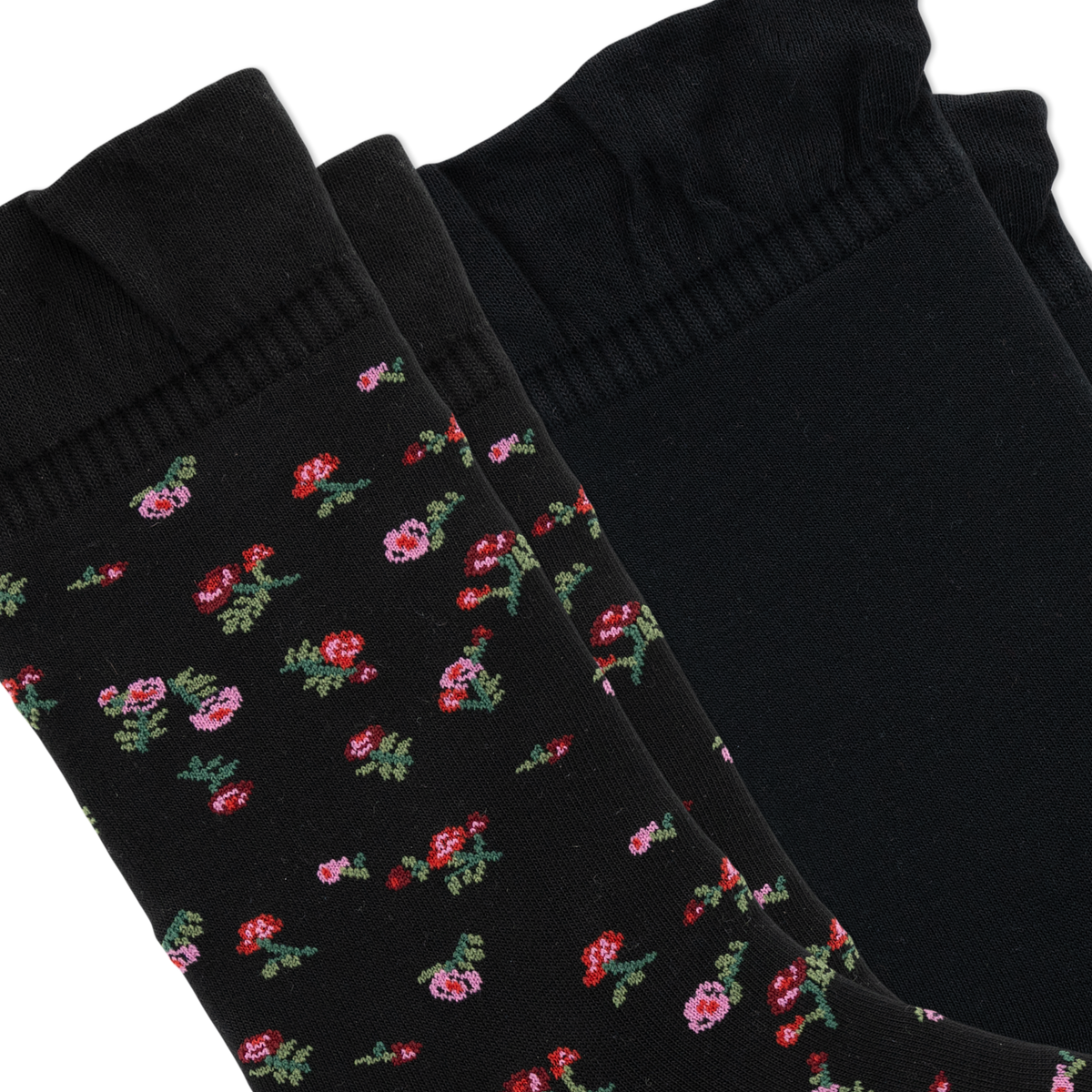 Two black socks arranged diagonally on a white background, with two featuring a small pink and red floral pattern with green leaves and one solid black sock.