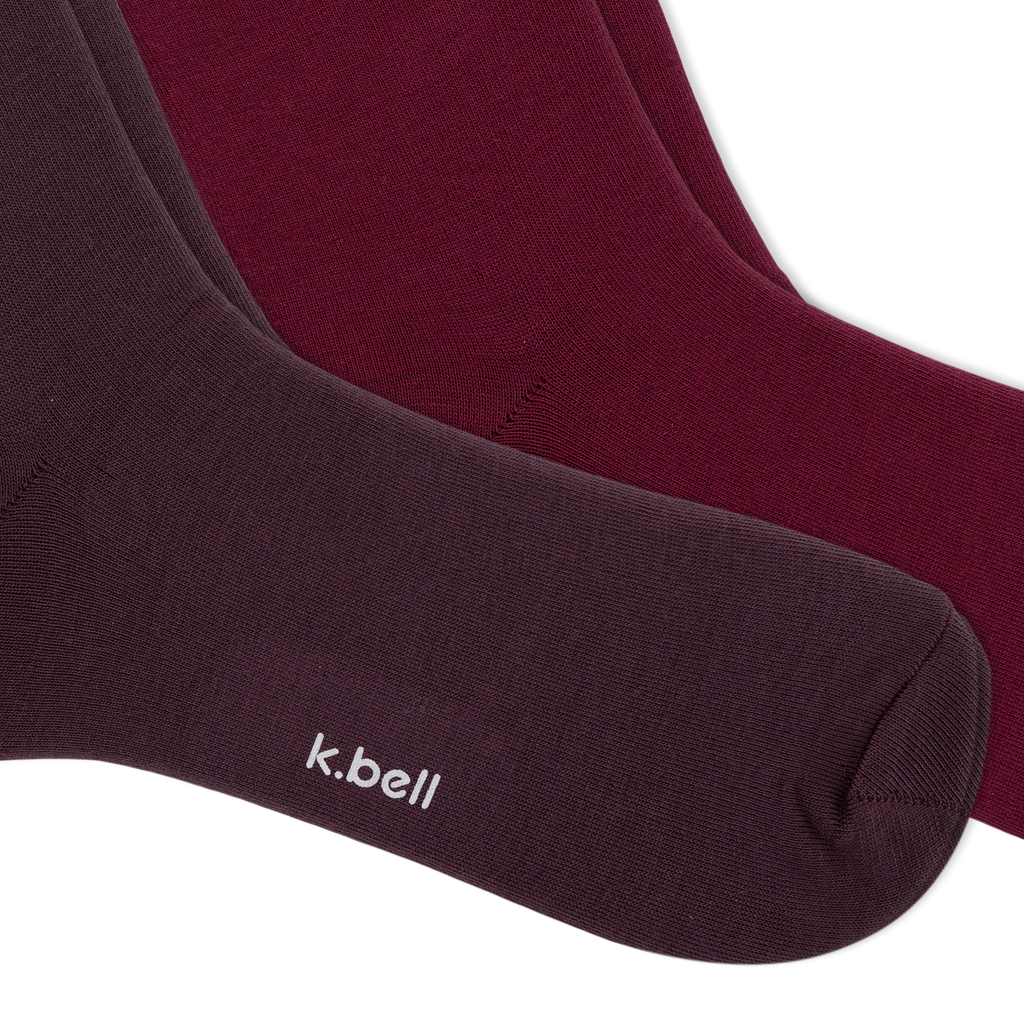 Two pairs of crew socks from k.bell, fanned out on a white background, with three tiers of ruffled colors from dark plum to burgundy, maroon, and dusty pink.
