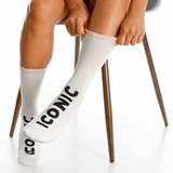White socks with 'Iconic' text worn by a person sitting on a chair. thumbnail