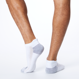 Back profile of a person wearing white MERRELL socks with black and gray accents on the heel and toe.