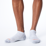 Front profile of a person wearing light gray MERRELL socks with orange and gray accents on the heel and toe thumbnail