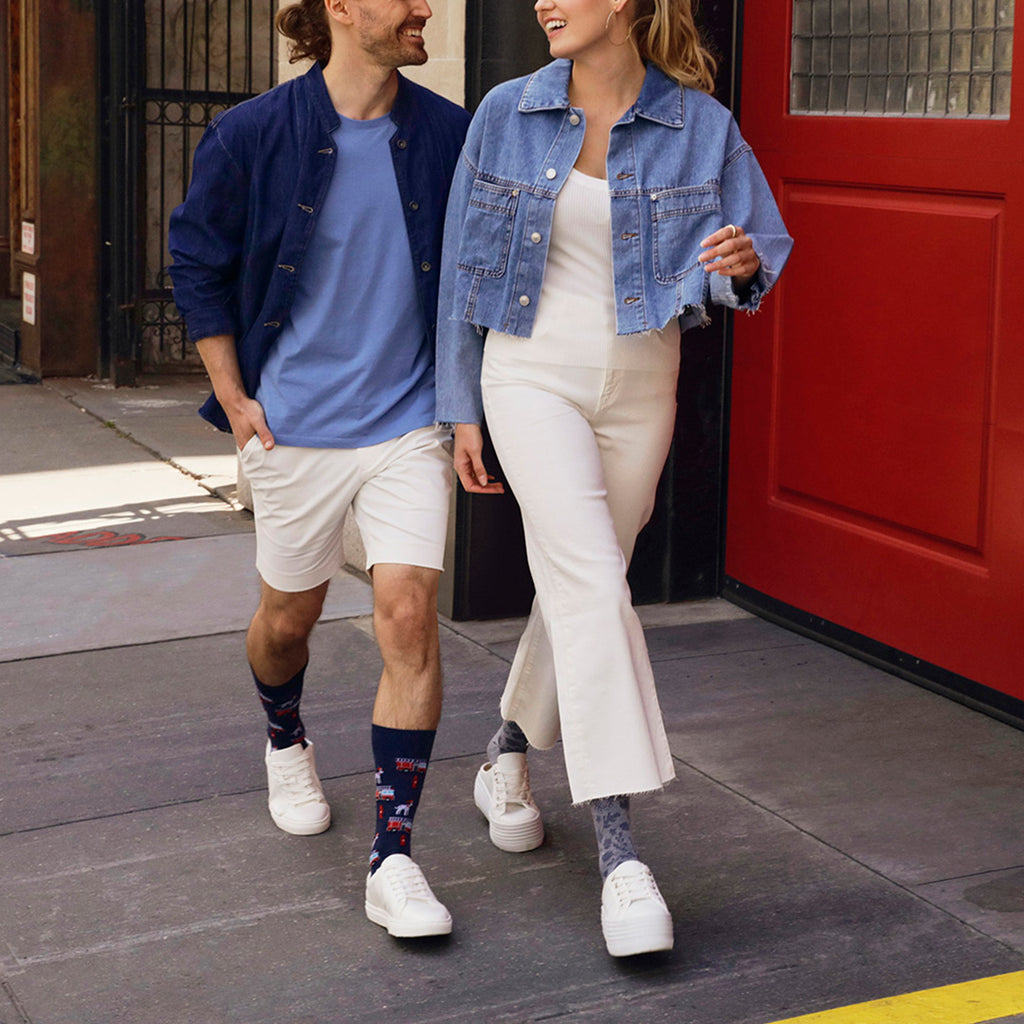 Two people walking on a sidewalk wearing denim jackets and white pants.