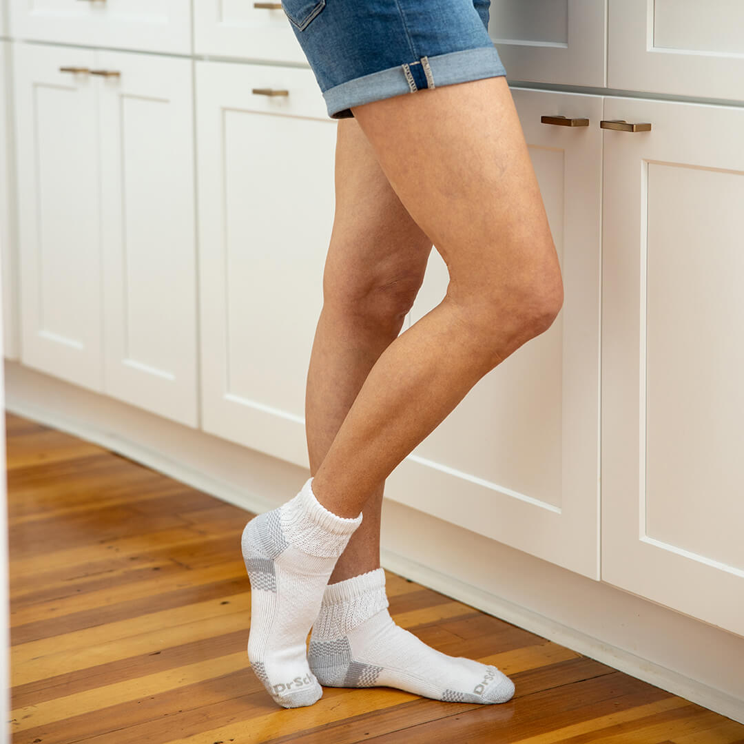 Person wearing white socks with gray patterns in a kitchen setting