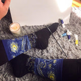 Person wearing socks with a Starry Night design on a textured surface with a candle and items. thumbnail