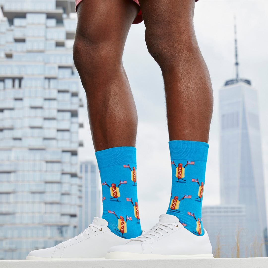 Person wearing blue socks with hot dog design in front of a city skyline