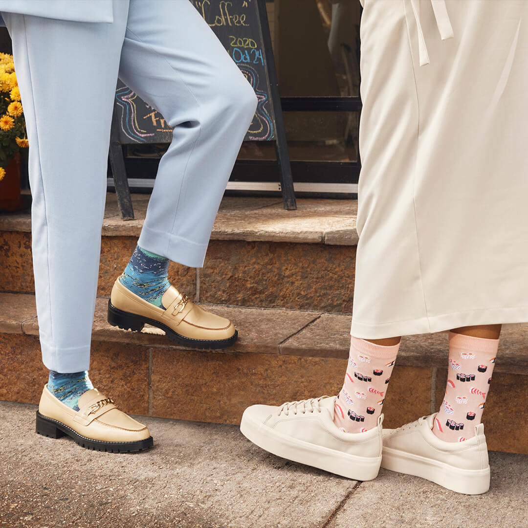 Two people standing on steps, wearing colorful socks and different types of shoes.