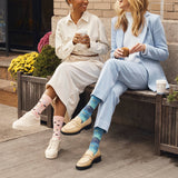 Two women sitting on a bench wearing colorful socks, one with pink polka dots and the other with a starry pattern. thumbnail