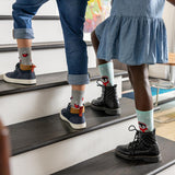 Two children wearing socks with cartoon characters on a staircase.