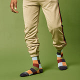 Person wearing beige checkered pants and multicolored socks on a green background