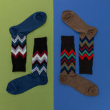 Two pairs of socks with zigzag chevron patterns on a green and blue background
