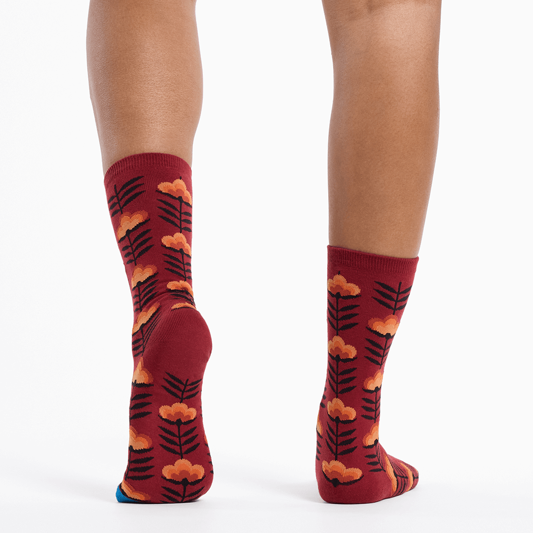 Red socks with floral pattern worn by a person on a white background