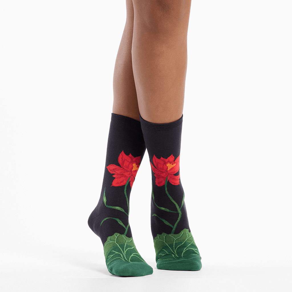 Black socks with red flower designs worn by a person on a white background