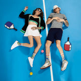 Two people lying on a blue surface with pickleball equipment around them. thumbnail